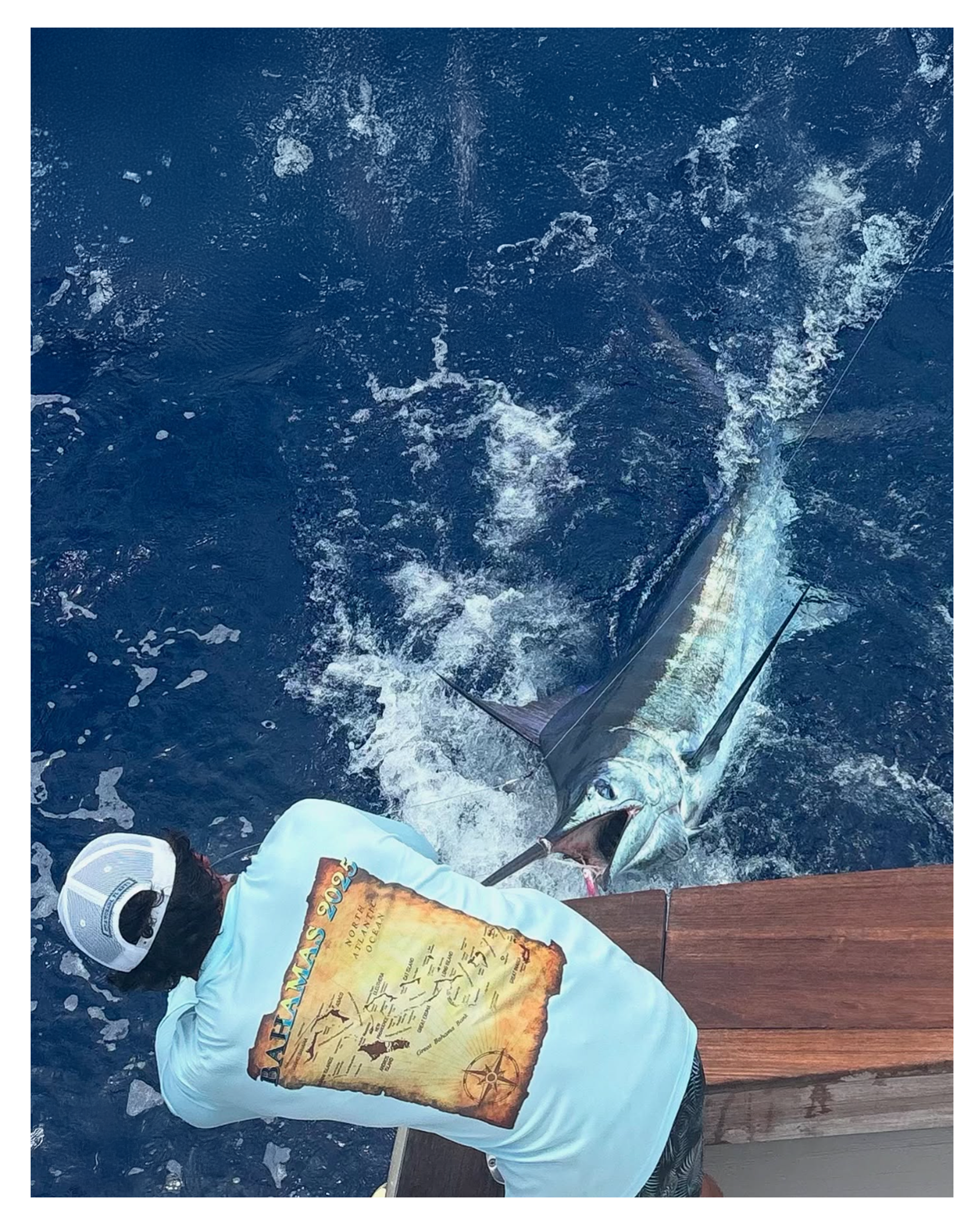 Angler in custom fishing apparel beside a billfish